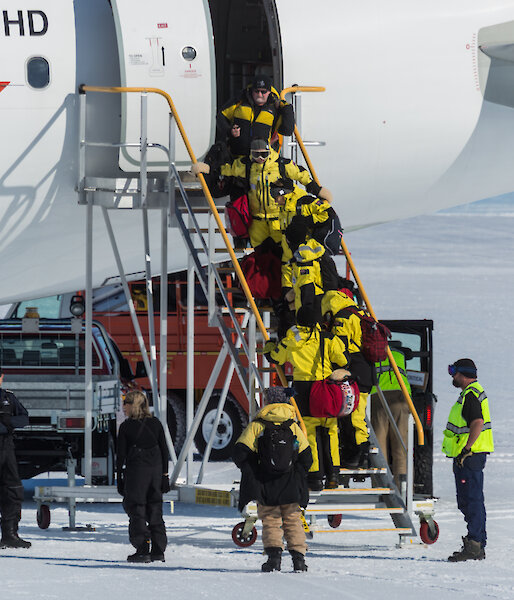 Passengers boarding gangway of aircraft on ice runway