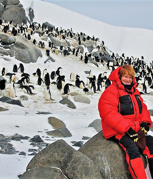 Artist sitting on rocks with Adélie penguins in background