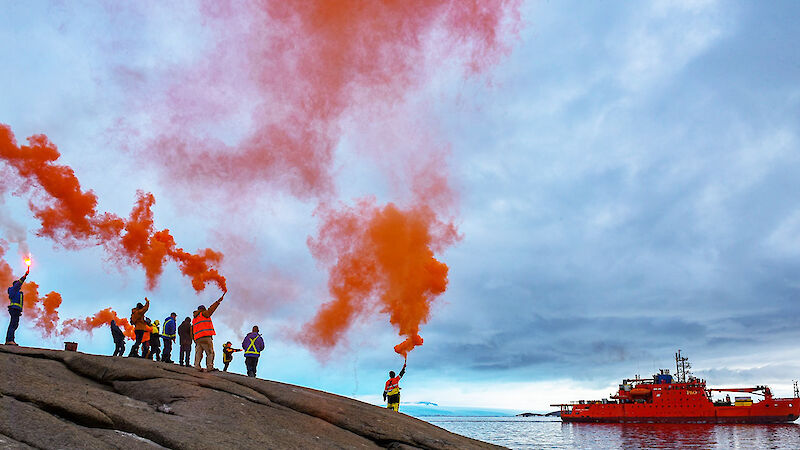 Expeditioners holding up flares to farewell the Aurora Australis icebreaker