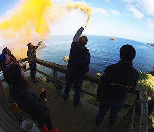 Expeditioners holding up flares to farewell the Aurora Australis icebreaker