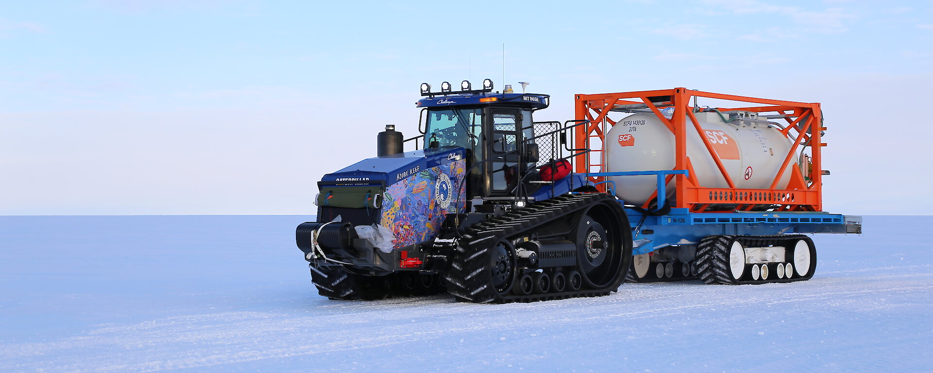 A colourful tractor in a snow covered landscape.