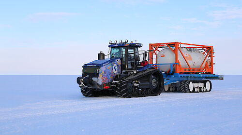 A colourful tractor in a snow covered landscape.