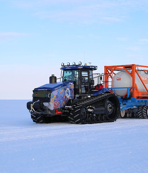 A colourful tractor in a snow covered landscape.