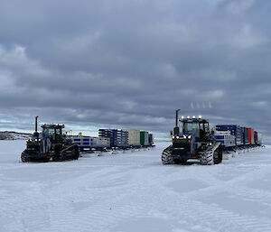 2 tractors tow long trains of shipping containers across the ice.