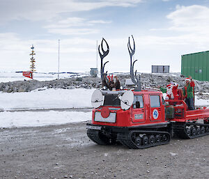 A Hagg decorated as a reindeer arrives at the Red Shed with Santa and his helper elves on the back