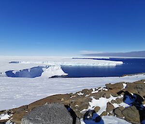 snow covered rocks and a glacier surrounded by water