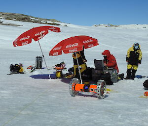 Three scientists preparing robotics equipment on the ice