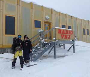 Two people in cold weather gear standing outside a building