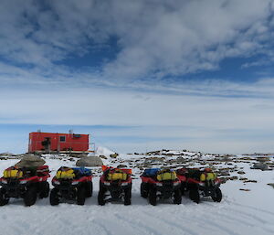 quad bikes parked in front of a field hut.