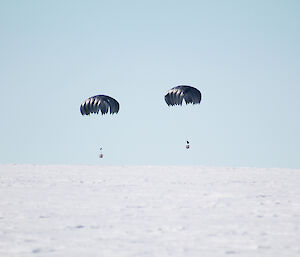 Two parachutes and loads about to touch down on the ice