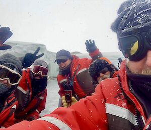 A team of masked expeditioners in a small boat pose for a photo.