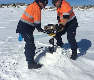 Two plumbers drilling a hole to find water