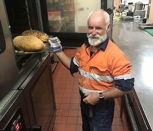 An expeditioner removing bread from the oven