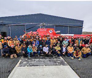 The Davis cohort pose in front of a red helicopter for a snowy, Christmas themed group photo.