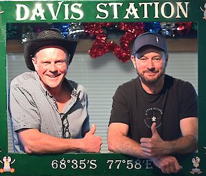Scientists Irv and Glenn getting photographed within the green, Davis Station themed photo booth at the new year’s eve party