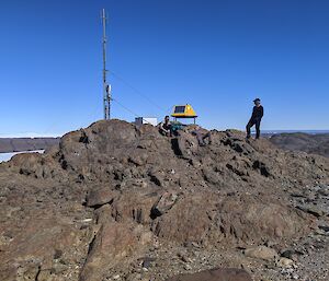 Three men sitting on rock summit