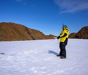 A man pulls on a rope on the snow and ice.