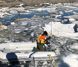 A surveyor in an inflatable rubber boat measures the Davis boat ramp depth