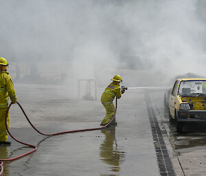 Chef Donna dressed in firefighting attire extinguishes a blazing car at fire training