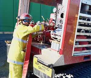 a man dressed in fire gear at the rear of the fire Hägglunds working the pipes