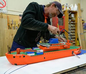 Carpenter makes a saw cut on his scale workshop model Aurora Australis ship