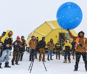 Group photo of exepditioners with one man holding holds a weather balloon