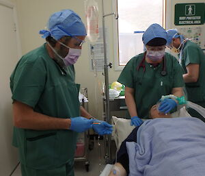 Three medical personnel and one patient lying in a bed