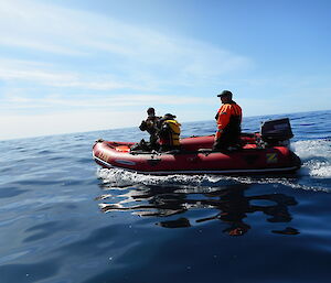 Three expeditioners in a zodiac boat in calm water