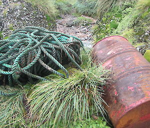 long, rolled up rope and rusty oil drum on the shore