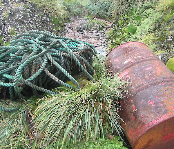 long, rolled up rope and rusty oil drum on the shore