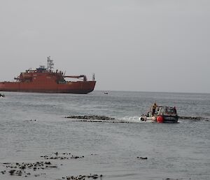 The icebreaker ship in the distance with an amphibious vehicle in front