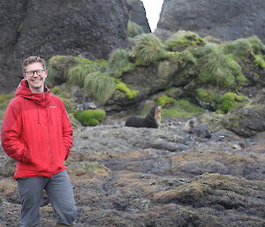 Expeditioner in front of a fur seal on the rocks