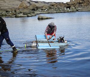 Two men in the water working on a homemade boat