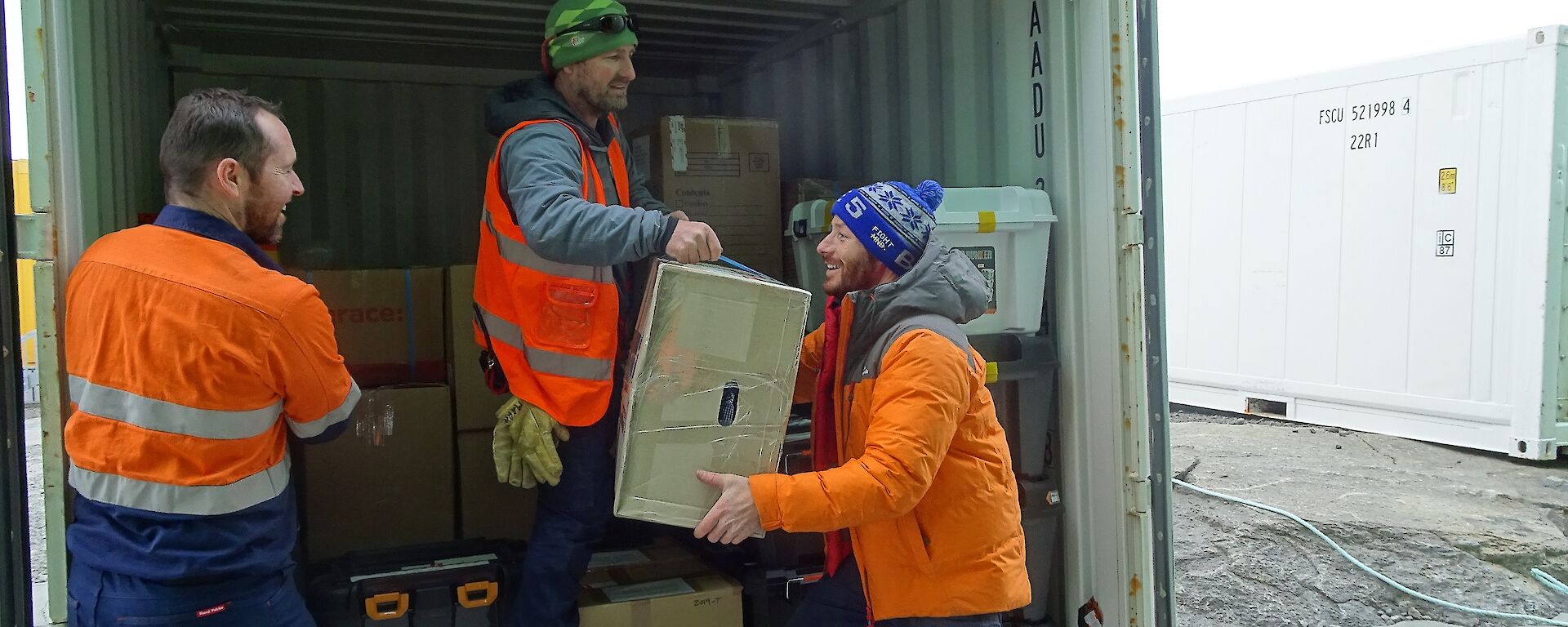 Three expeditioners unloading cargo from a shipping container