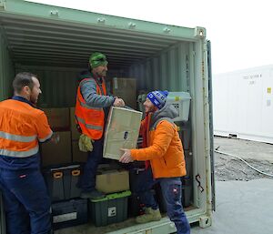 Three expeditioners unloading cargo from a shipping container