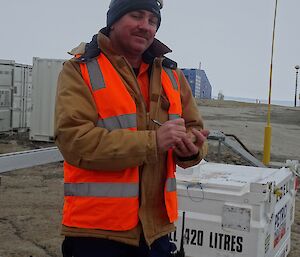 An expeditioner writing on a note pad in front of shipping containers