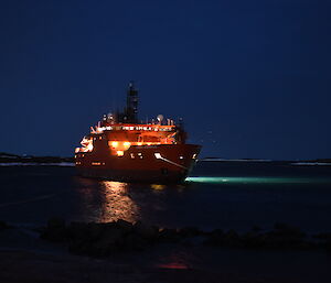 Ship with lights on in the harbour at night