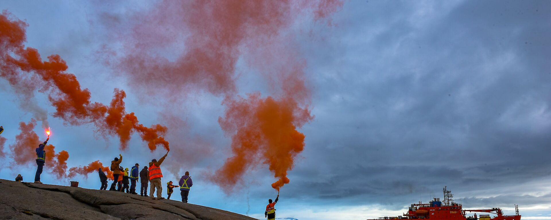 Expeditioners holding up flares as the ship departs