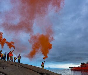 Expeditioners holding up flares as the ship departs