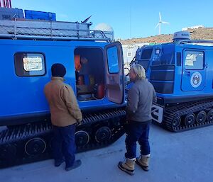 Two expeditioners looking at Hägglunds on station