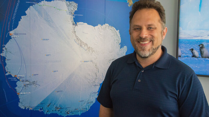 Australian Antarctic Data Centre Manager Dr Johnathan Kool in front of Antarctic map.