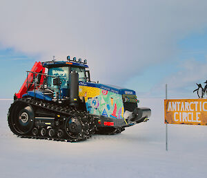 One of the traverse tractors at the Antarctic Circle sign.