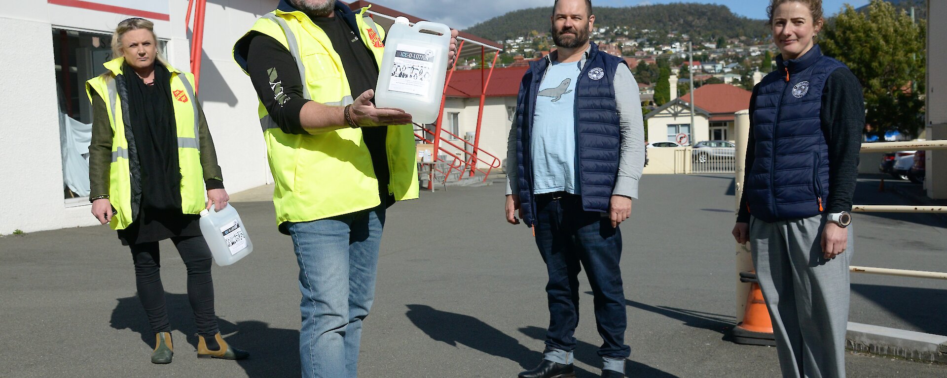 A group of people holding large bottles of hand sanitiser.