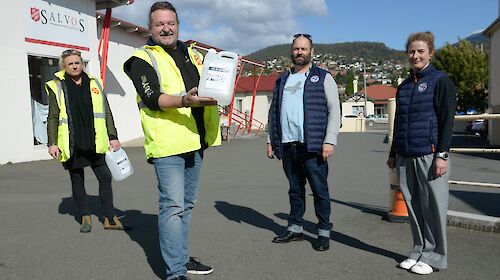 A group of people holding large bottles of hand sanitiser.