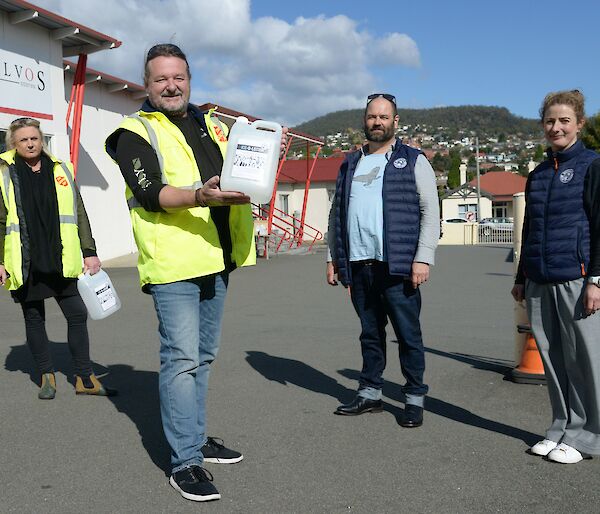 A group of people holding large bottles of hand sanitiser.