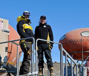 two researchers outside round orange hut