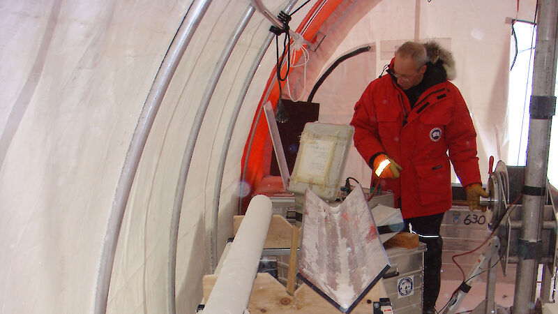 A scientist with an ice core in a drill tent in Antarctica.