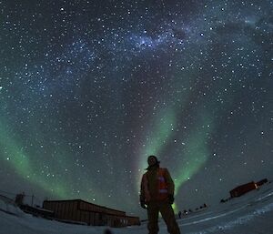 man stands with aurora in background