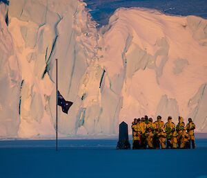 group of people on sea ice with cliff in background