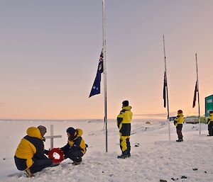 people with wreath and flagpoles at dawn